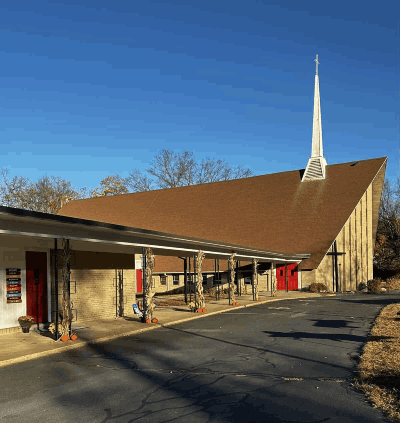 Front of Faith Lutheran Church with a wide covered sidewalk leading to the right to the main red doors of the church. Another red door is on the left leads to the education wing of the building.