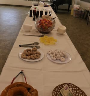 table in the Faith church's fellowship hall during coffee time after the service. Filled with donuts and fruit with bowls and utensils.